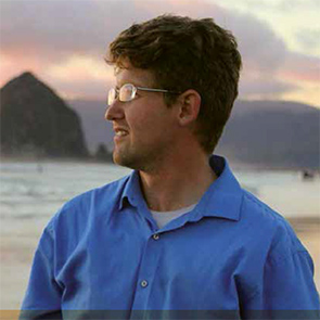 Man stares in mid distance with lake, mountain background